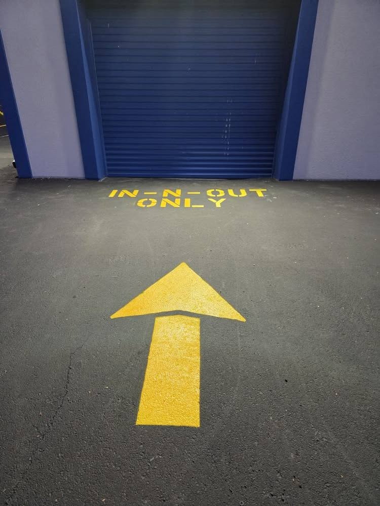 Yellow lettering and a large directional arrow stencilled at a roll-up door