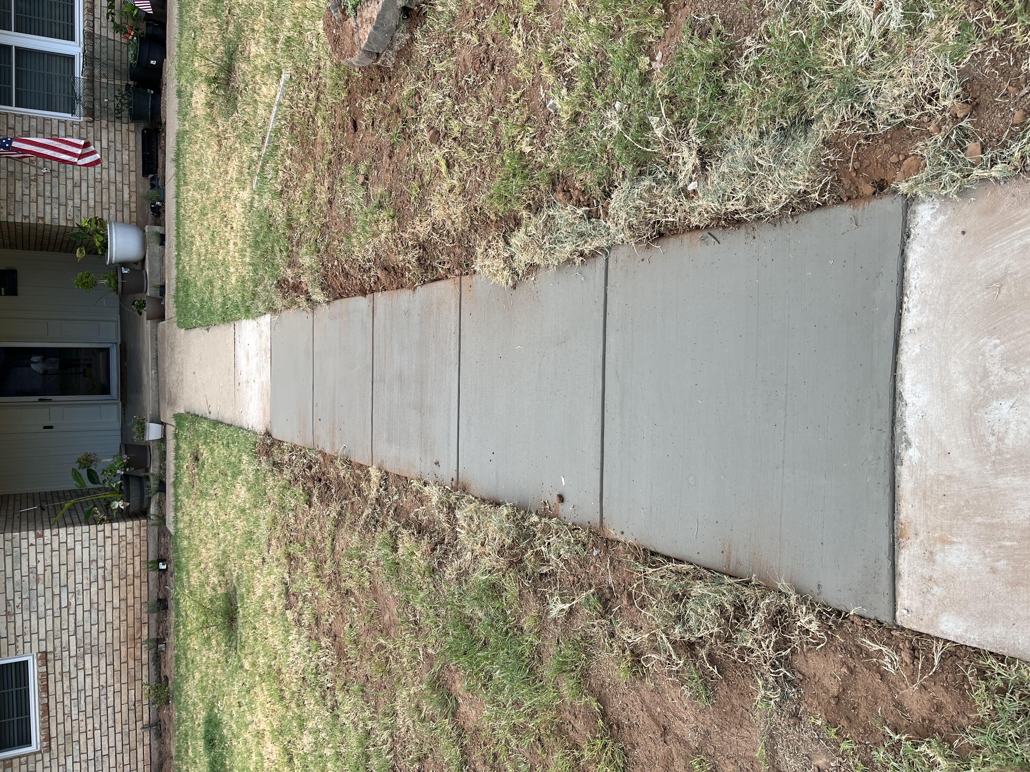 Concrete sidewalk walkway connecting driveway to porch by Rock of Ages Concrete LLC