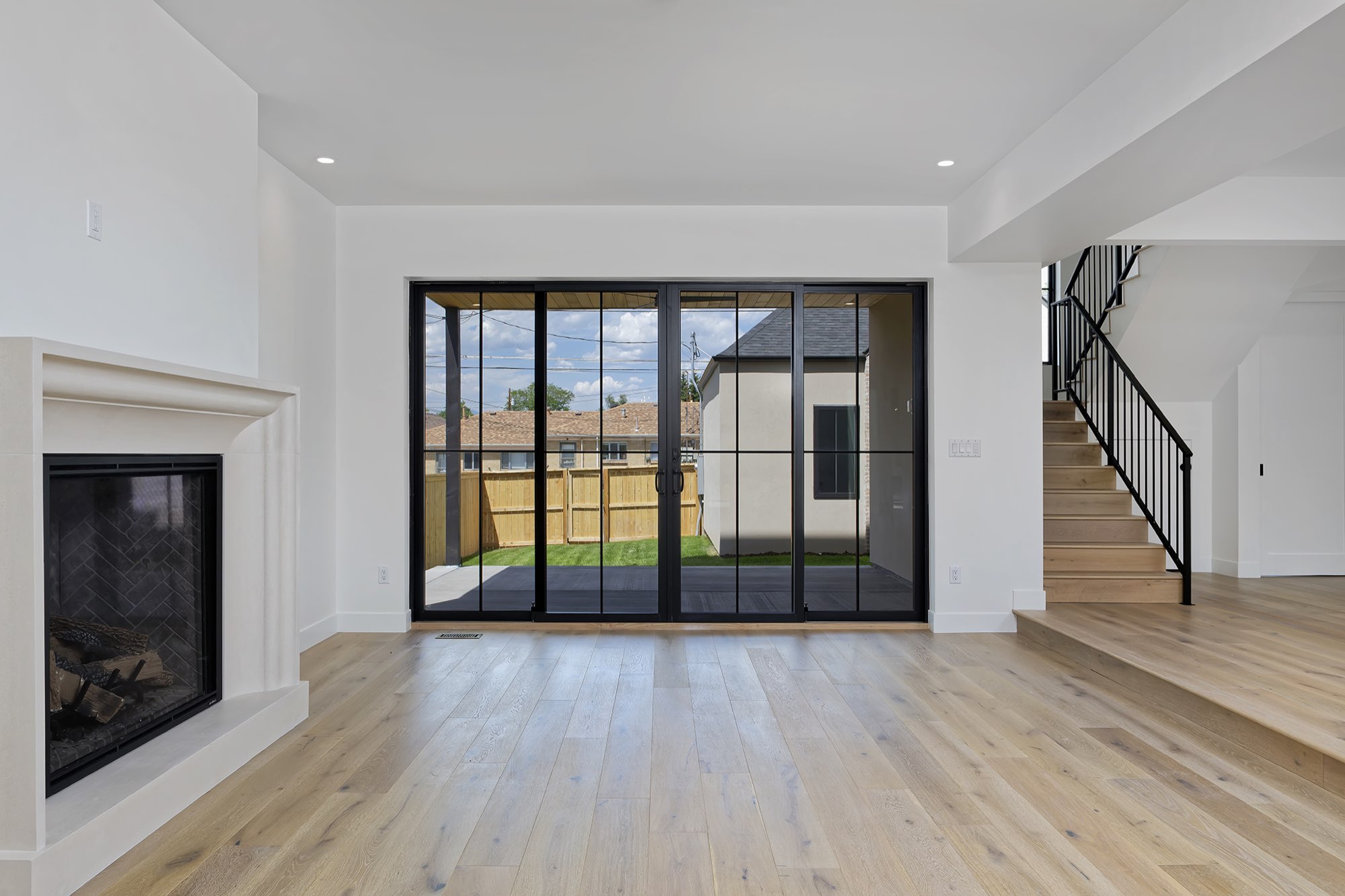 Black-framed sliding doors beside a fireplace, with wide steps up to a stair with a black iron railing