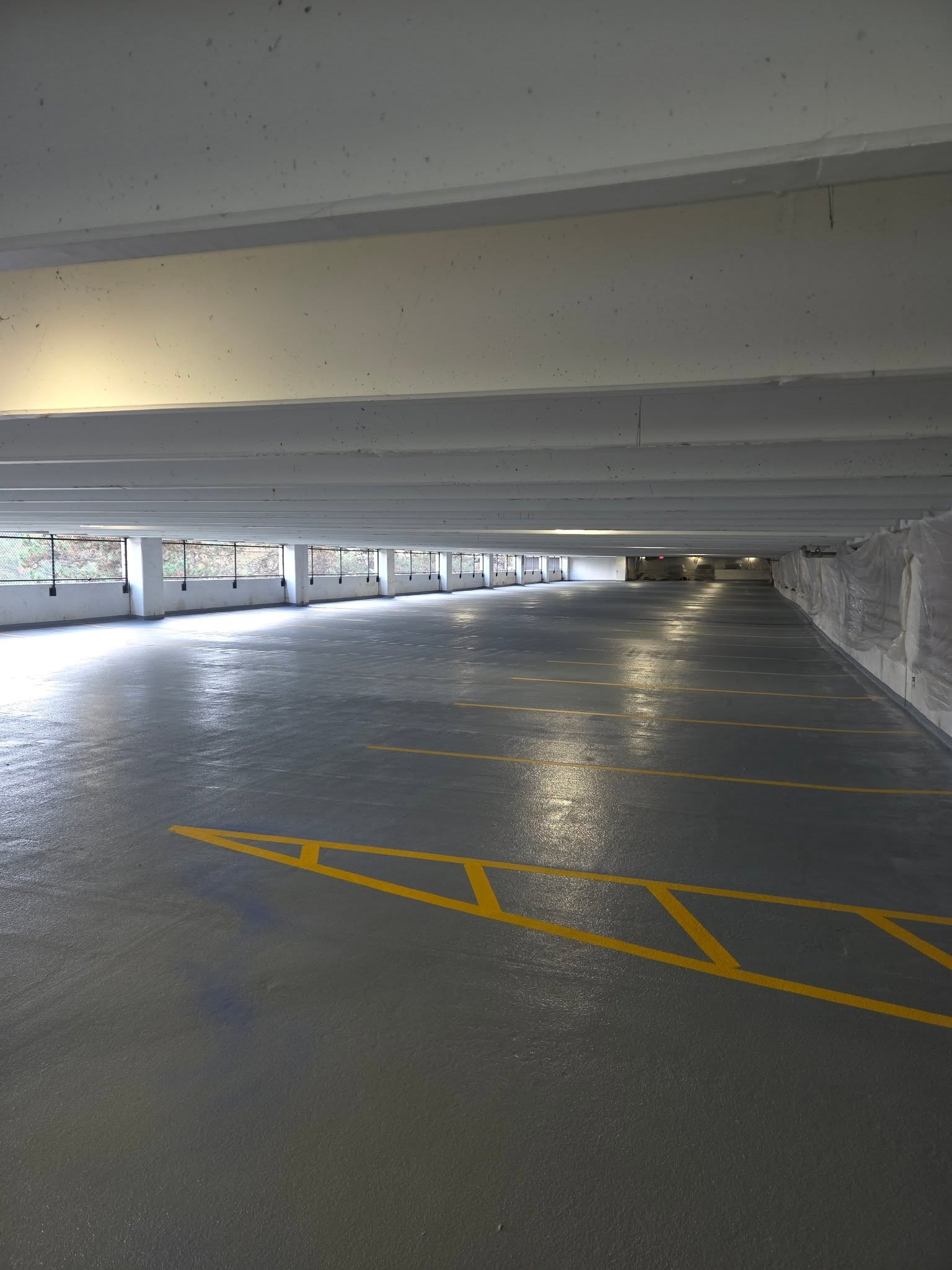 Fresh yellow hatch marking laid on a deck floor between the columns