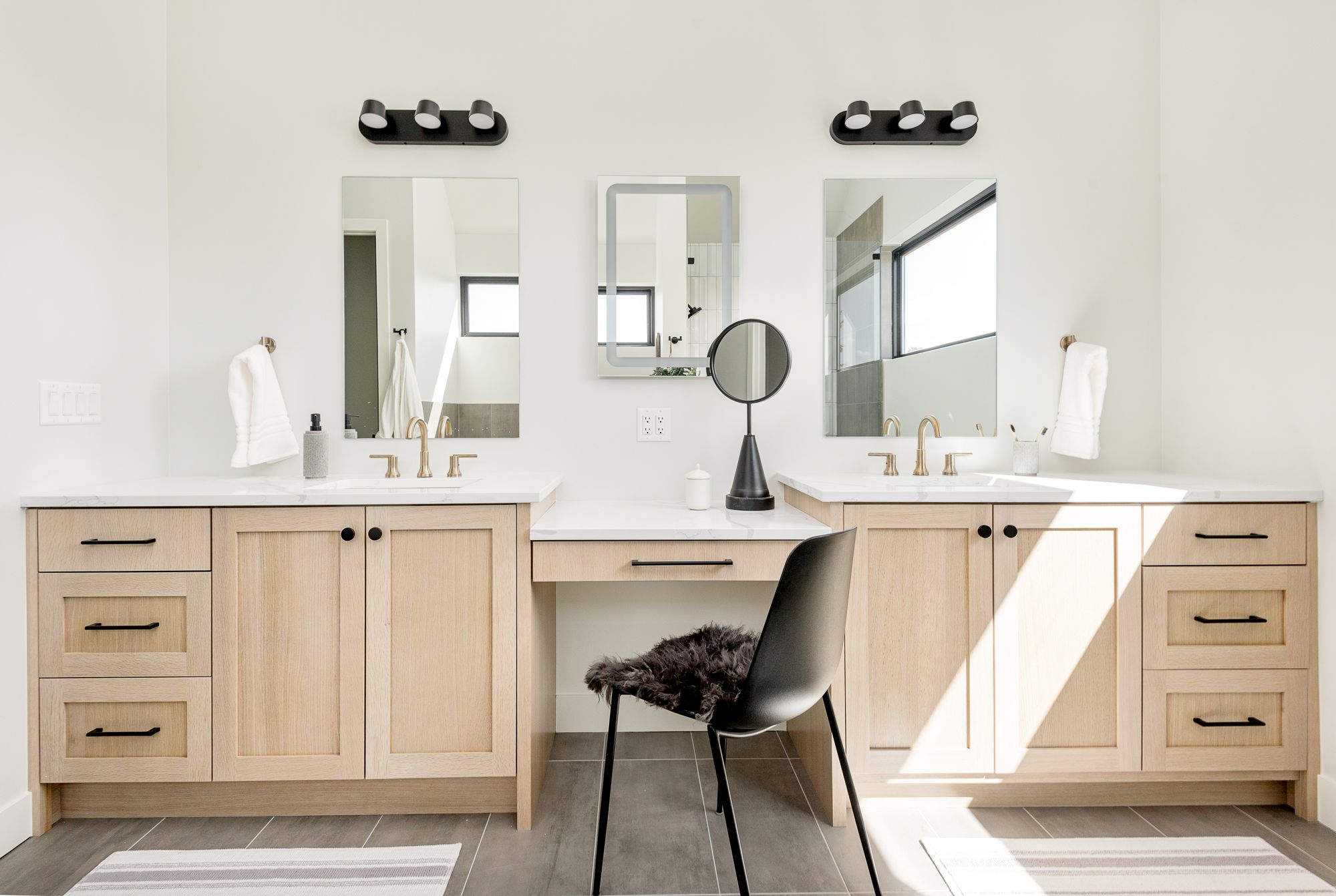 Primary bathroom double white oak vanity with a makeup station and black sconces