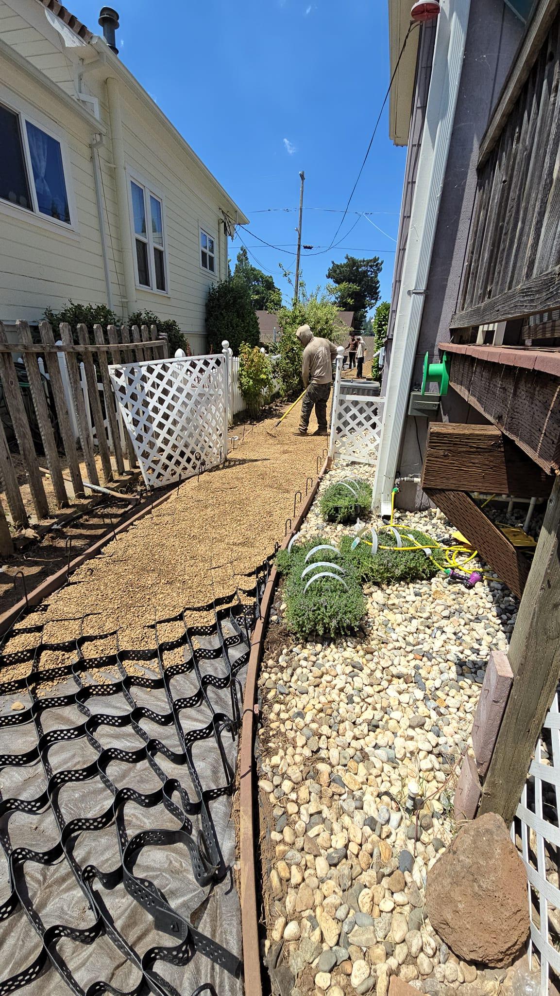 New gravel pathway with steel edging, river rock bed, drip irrigation and fresh plantings