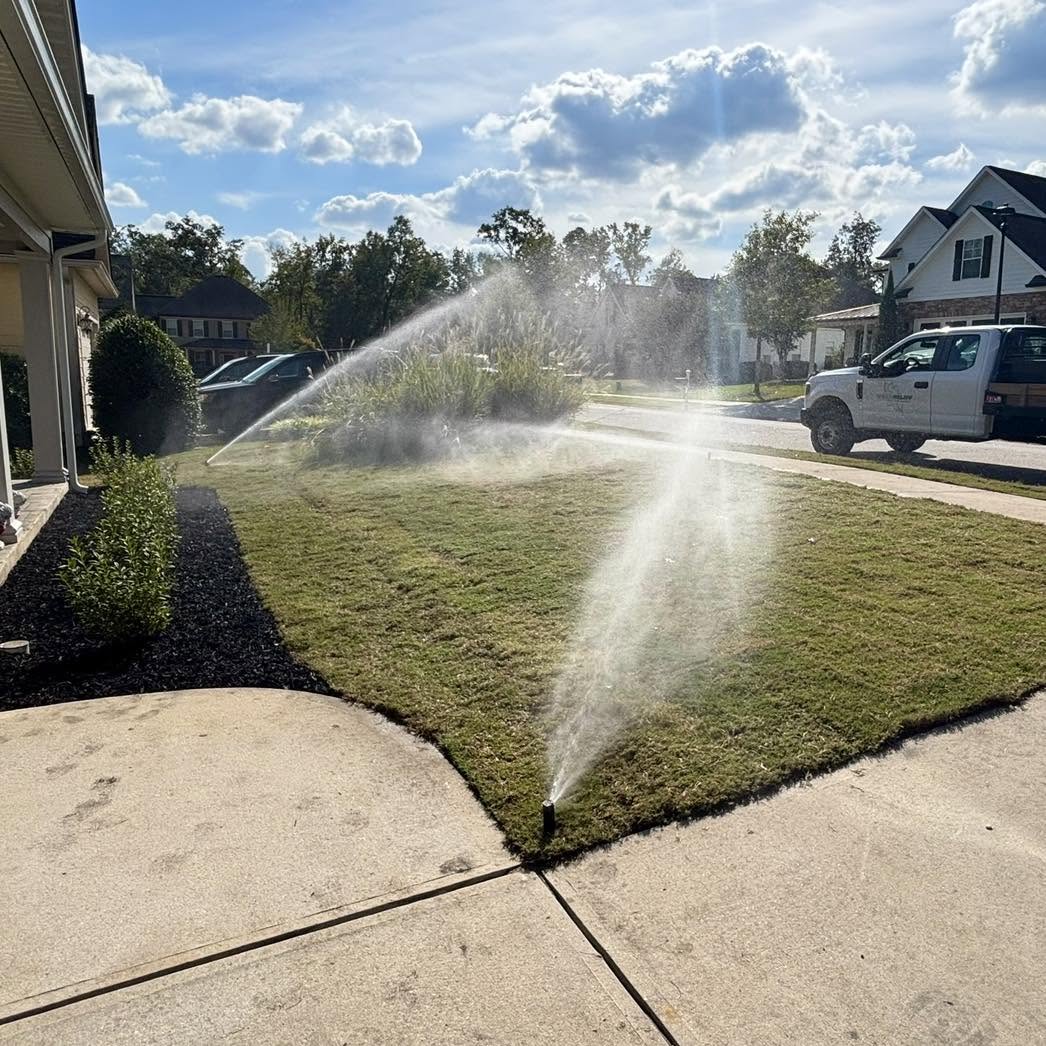 Irrigation sprinklers running across a green lawn