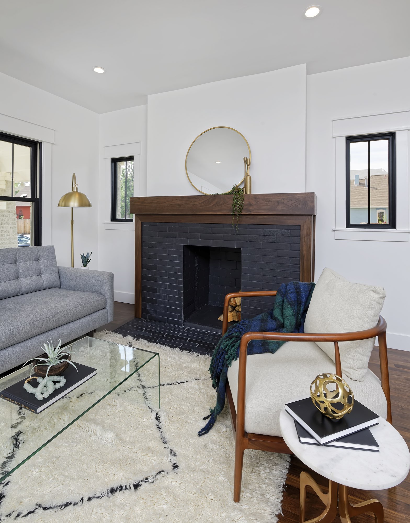 Close view of the dark brick fireplace, wood mantel and black-framed windows in the living room