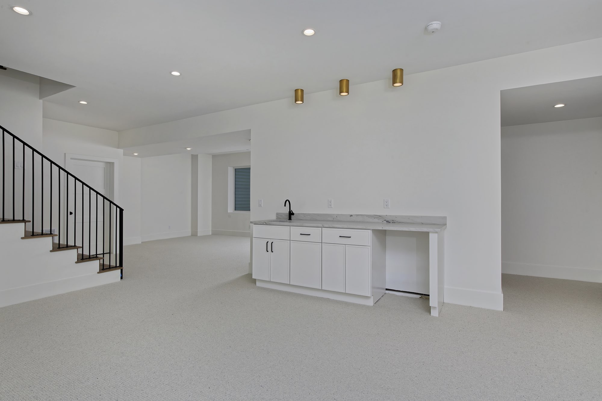 Lower level with a black-railed stair with wood treads and the wet bar with brass ceiling lights