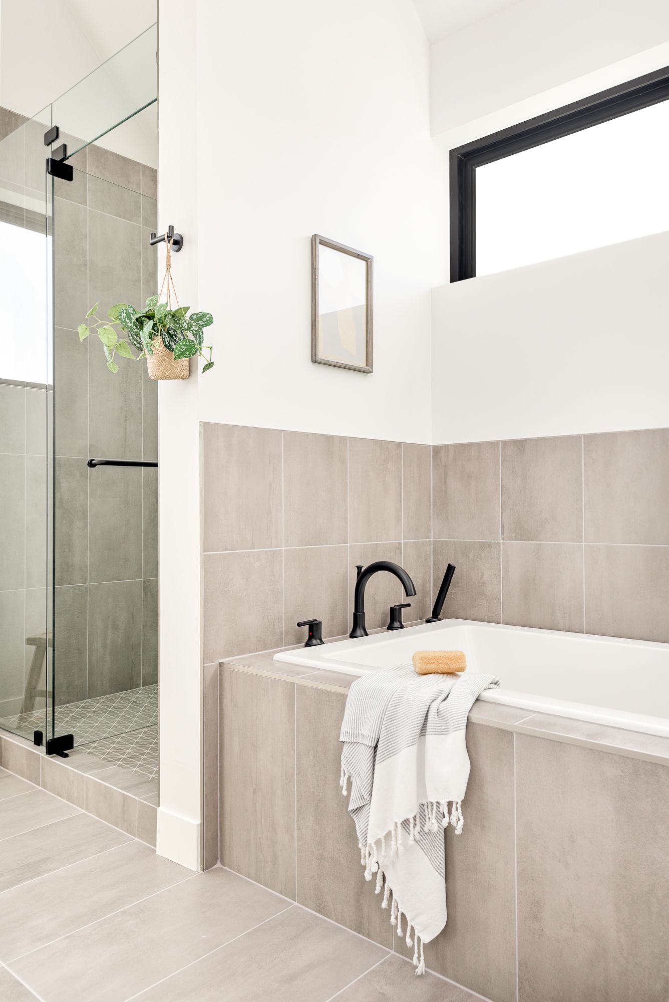 Primary bathroom with a glass walk-in shower in white vertical tile and a tiled soaking tub