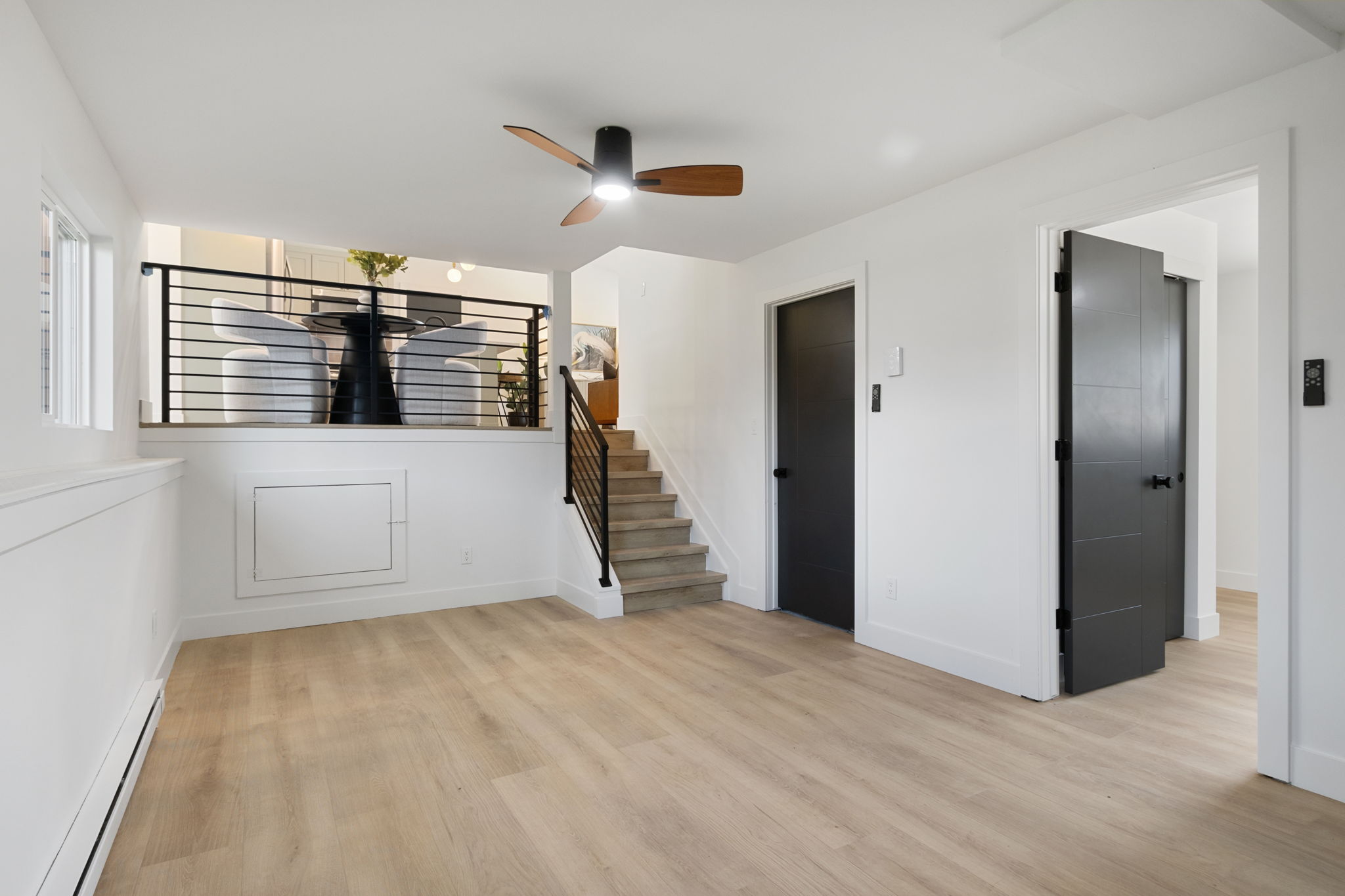 Stairs with a horizontal black metal railing leading up to the main level
