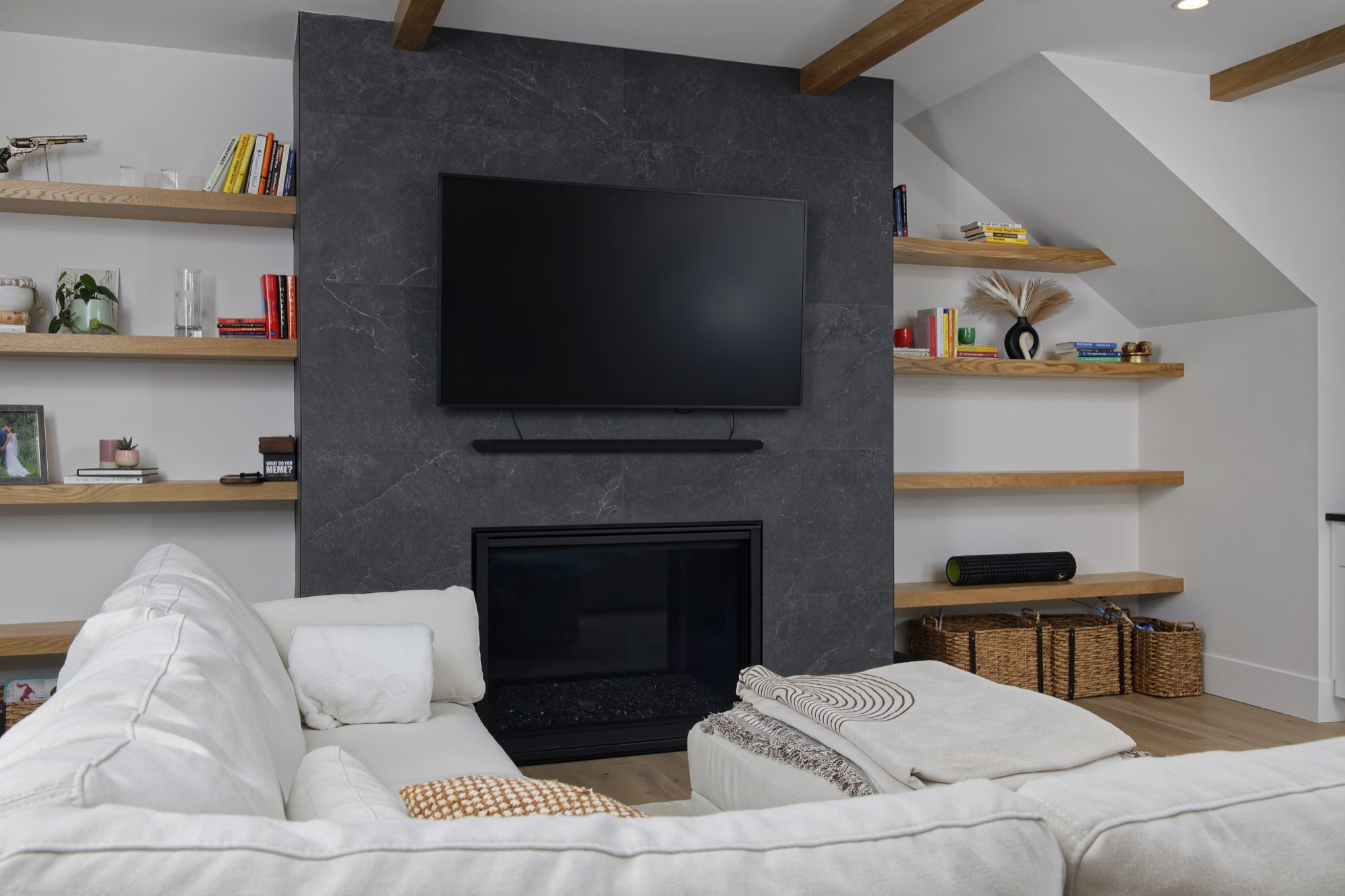 Fireplace wall with a wall-mounted TV and floating wood shelves on both sides