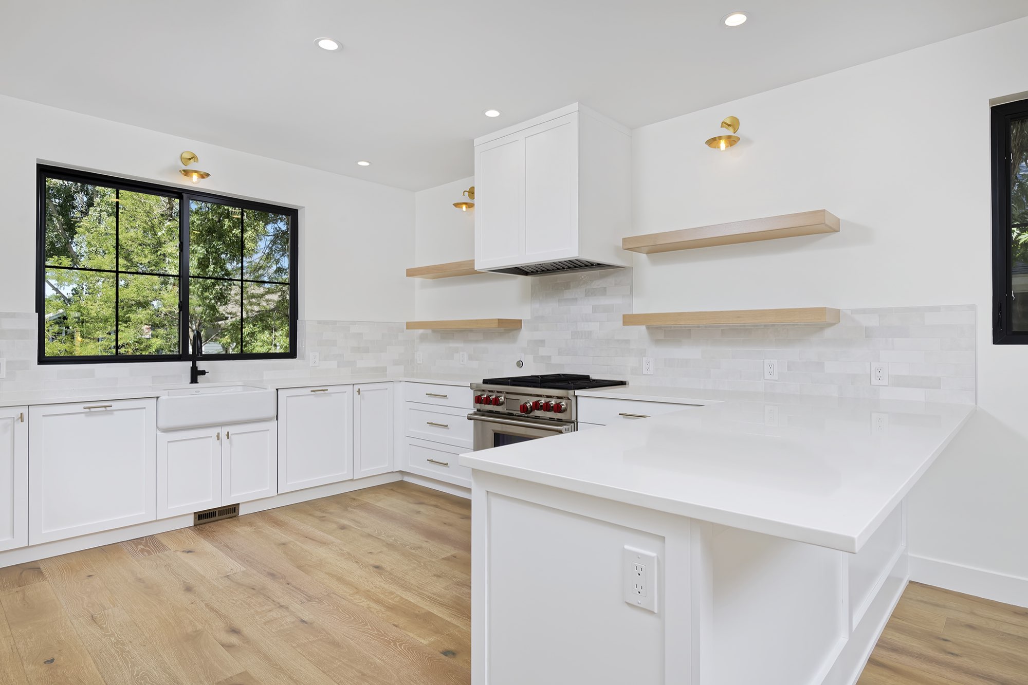 Kitchen corner with white cabinets, floating shelves, a peninsula and light wood floors