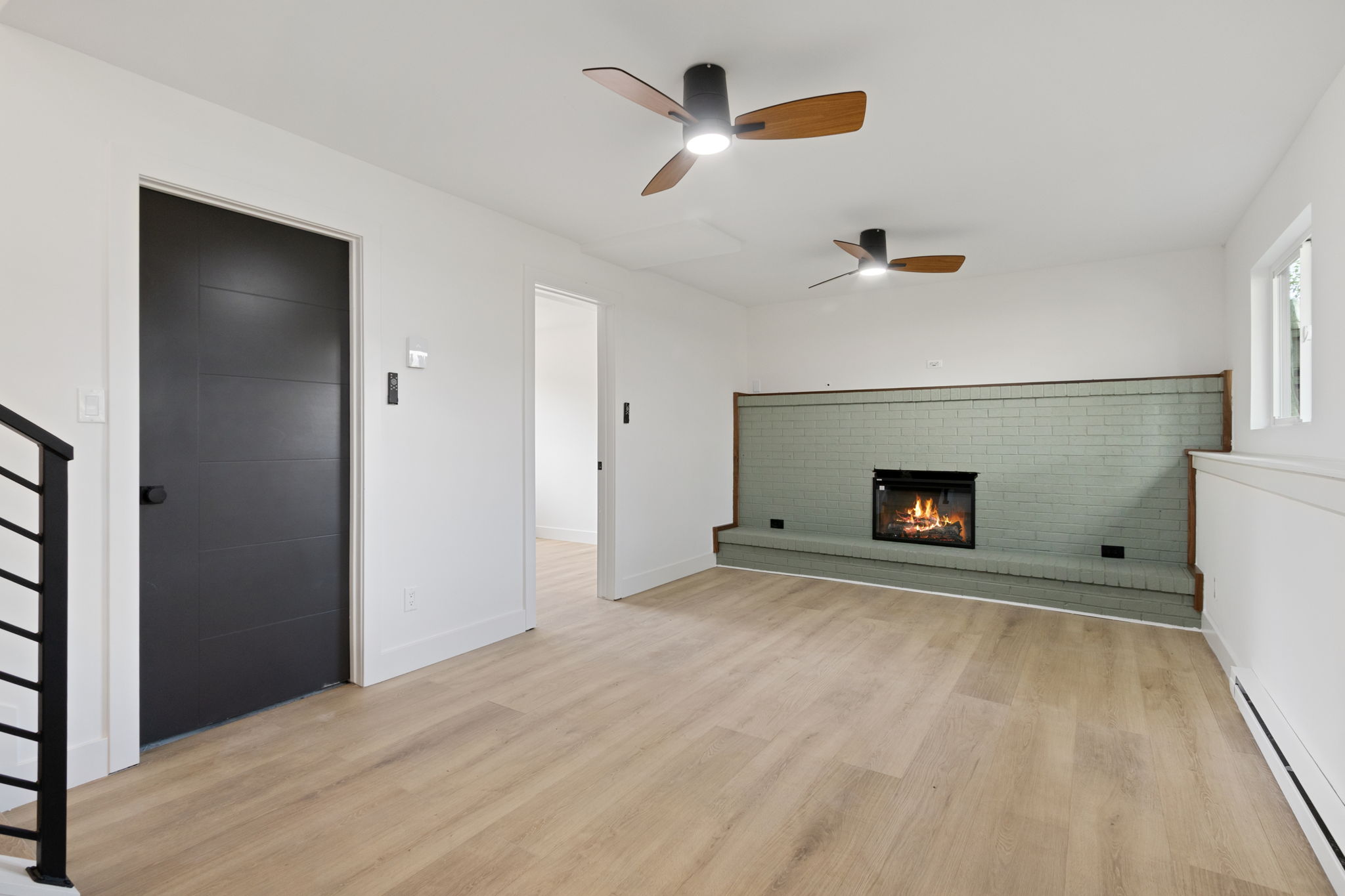 Lower-level family room with a brick fireplace wall painted sage green