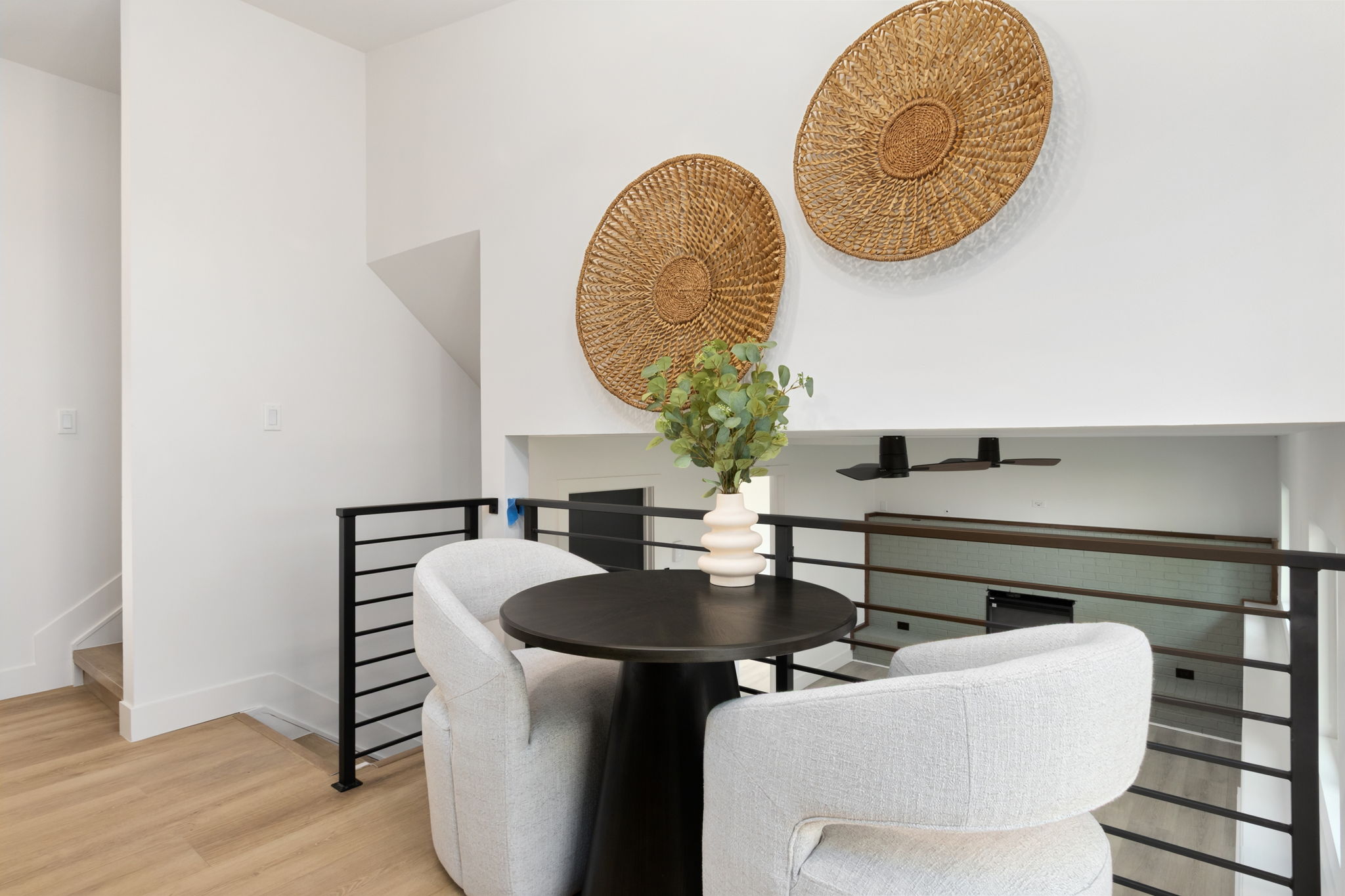 Dining nook beside the black metal stair railing with wicker wall plates