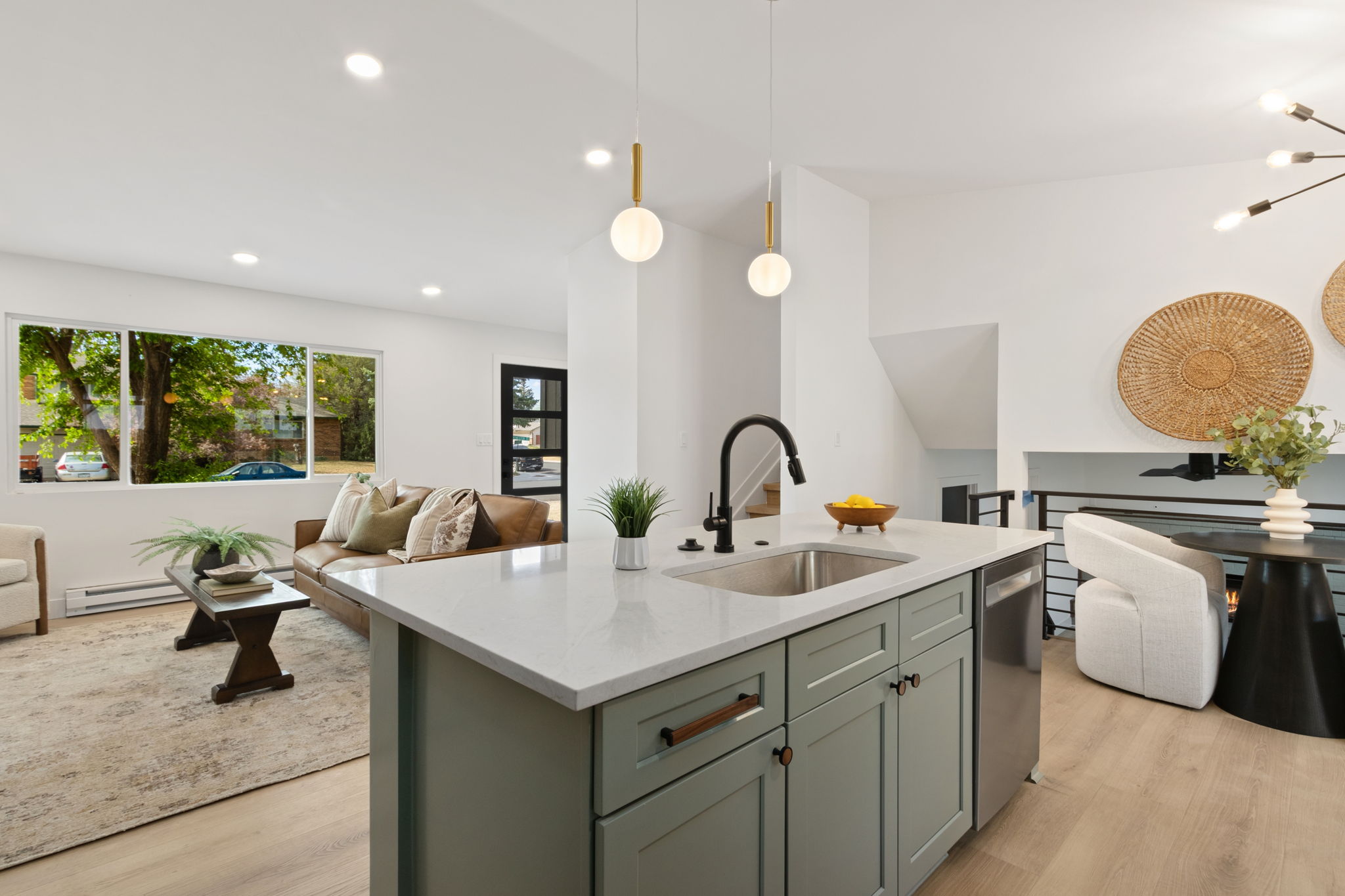 Sage-green island and brass globe pendants looking toward the living room windows