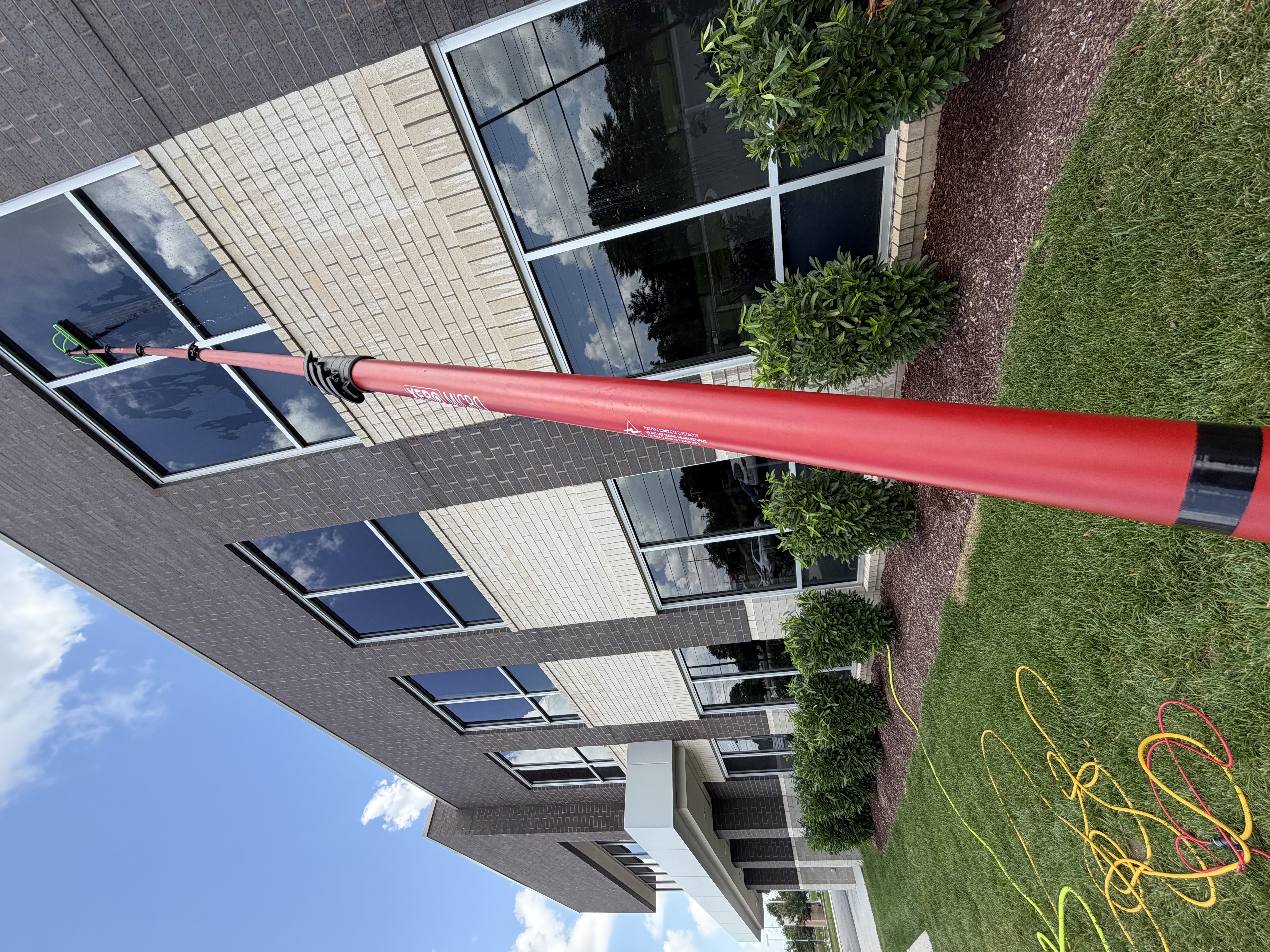 Water-fed pole reaching second-story windows on a brick commercial office building