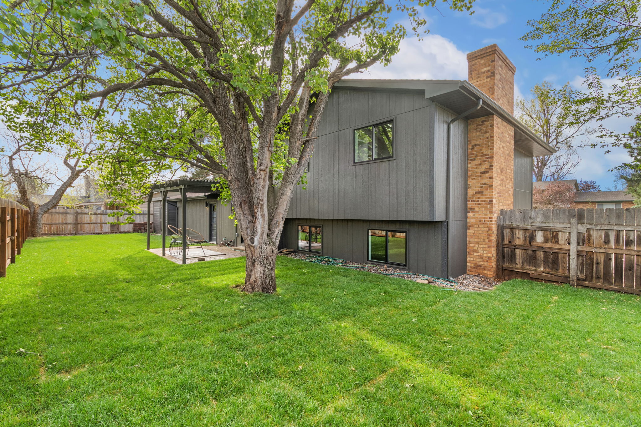 Back of the Fort Collins house with its brick chimney, a large shade tree and the lawn beyond
