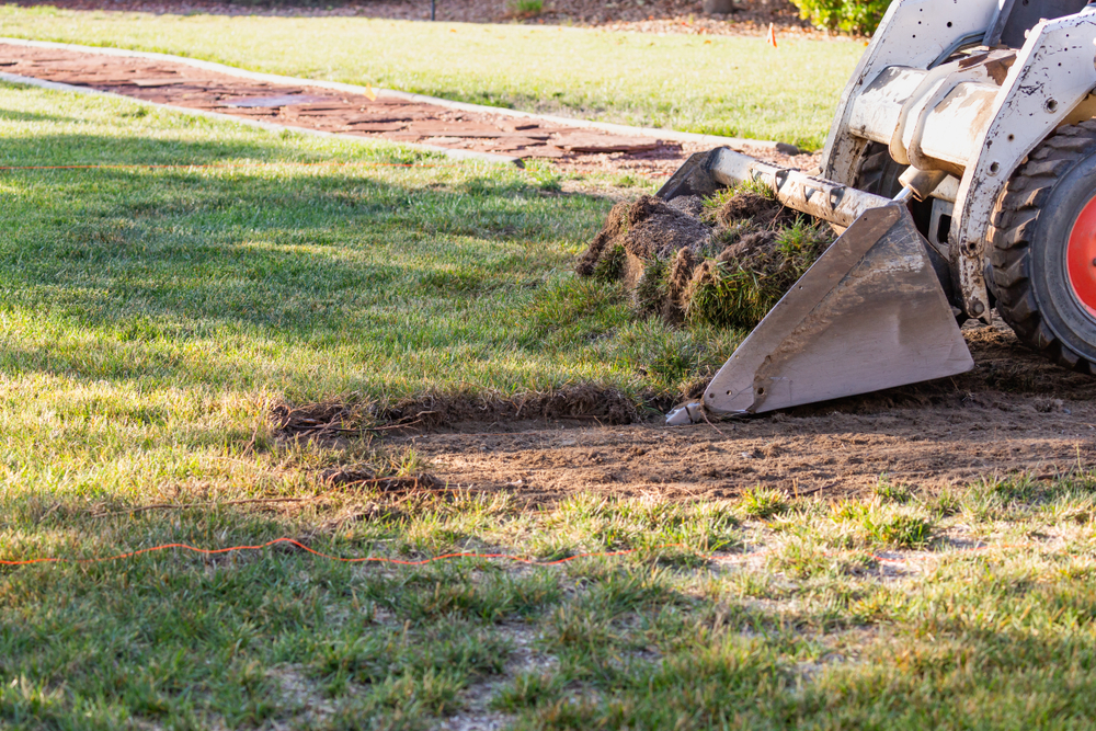Skid steer regrading a lawn