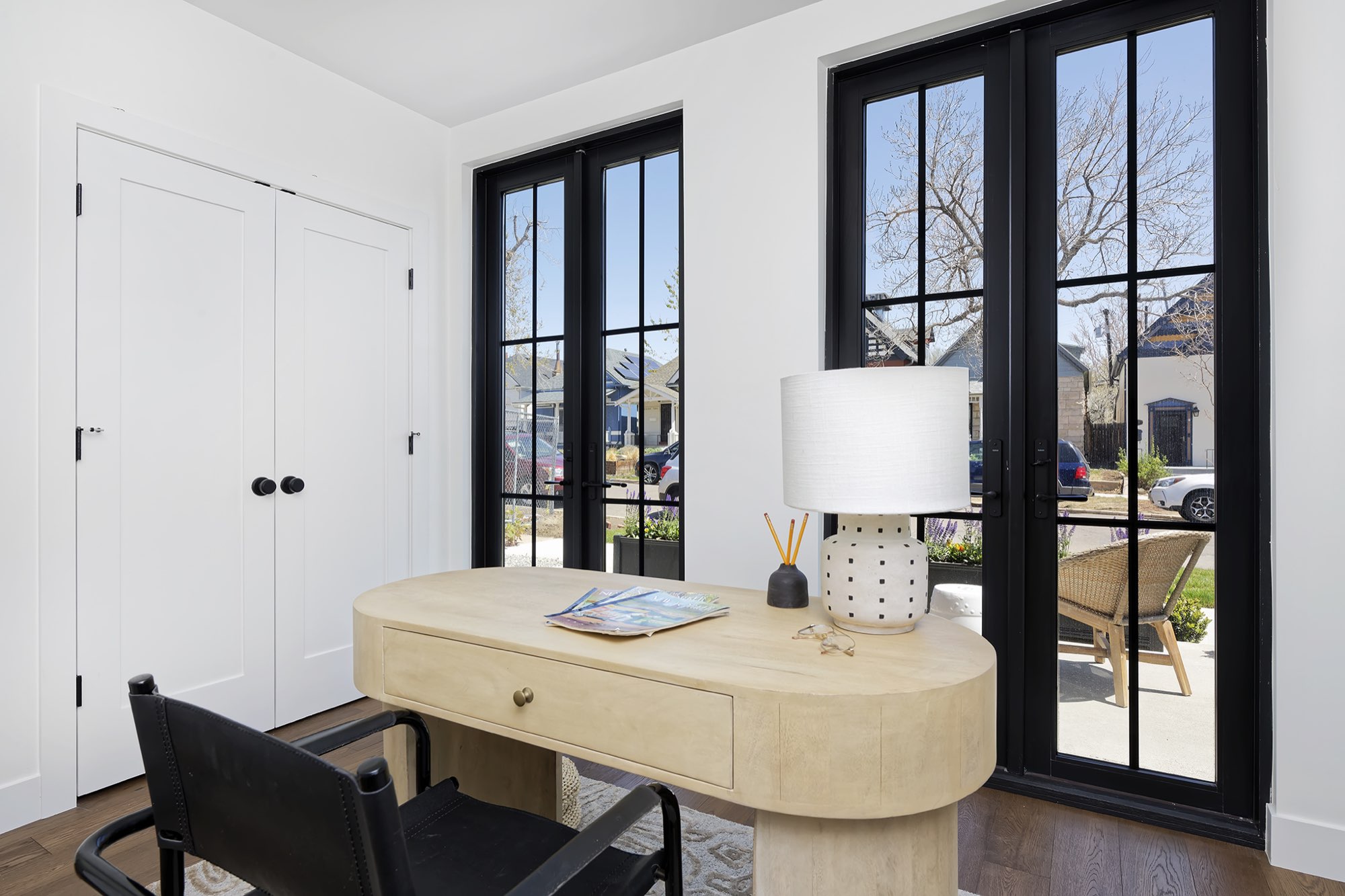 Small room with black-framed French doors, double closet doors and a desk, looking out to the front walk
