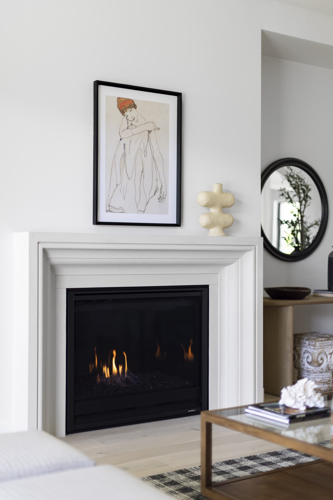 White fireplace with a deep mantle surround and a gas fire, framed art above