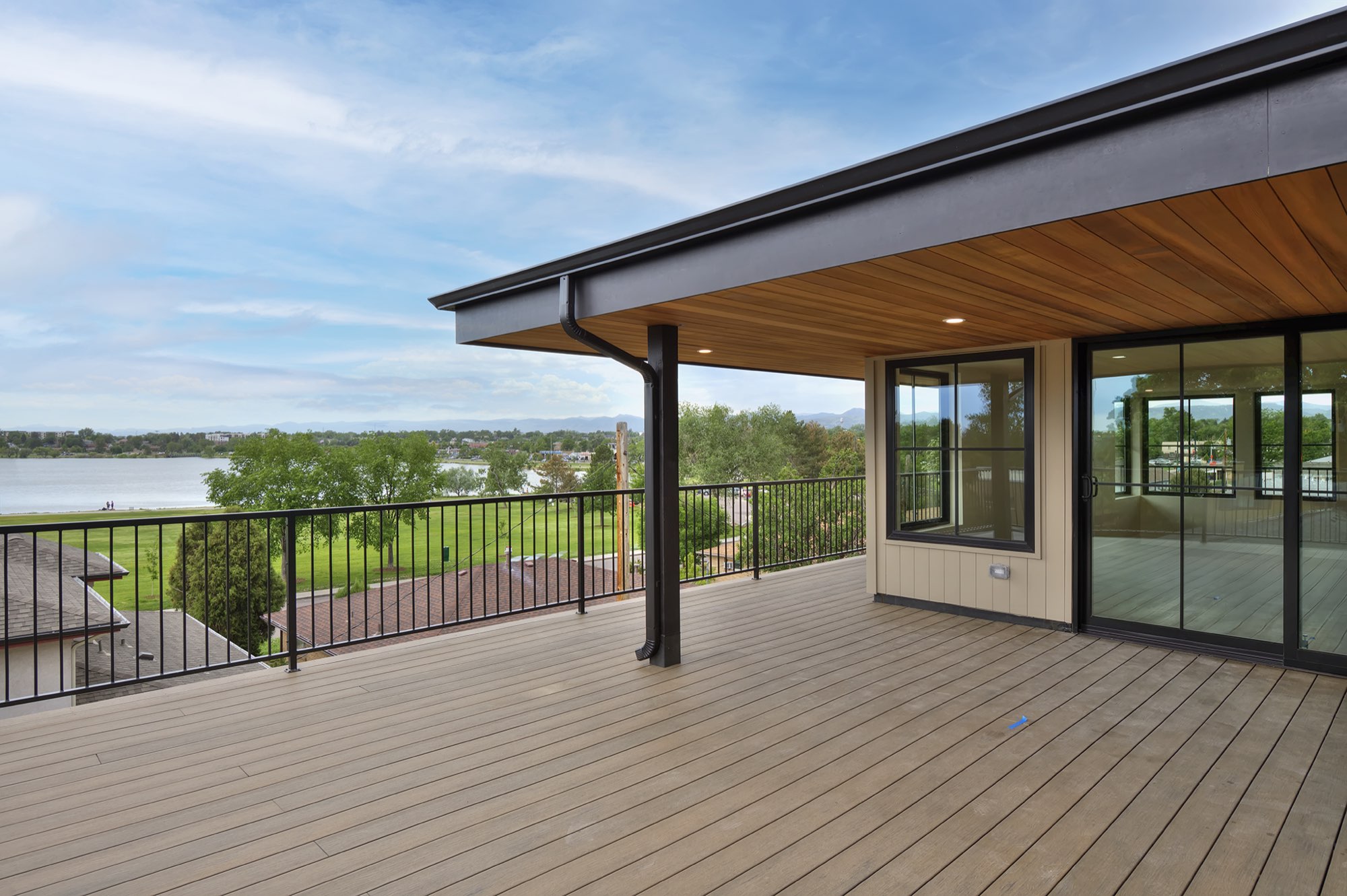 Deck with a black metal railing and a view across a park to the lake