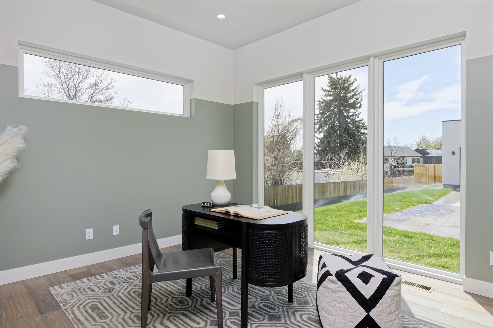 Office with sage green lower walls, a long window and a wall of glass looking onto the lawn