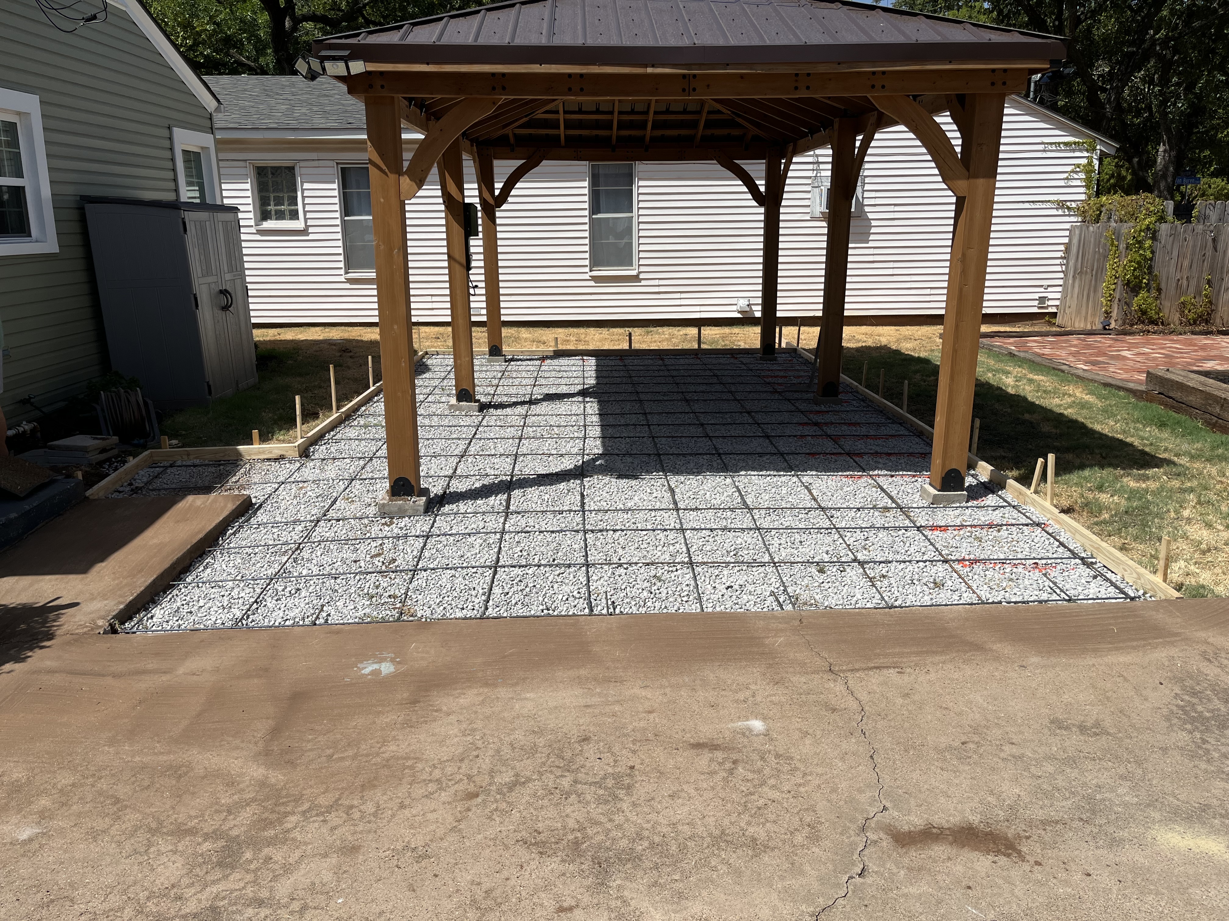 Completed concrete patio beneath a wooden pergola by Rock of Ages Concrete LLC